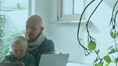 animación de palabras quedarse en casa sobre hombre caucásico con un niño usando su laptop