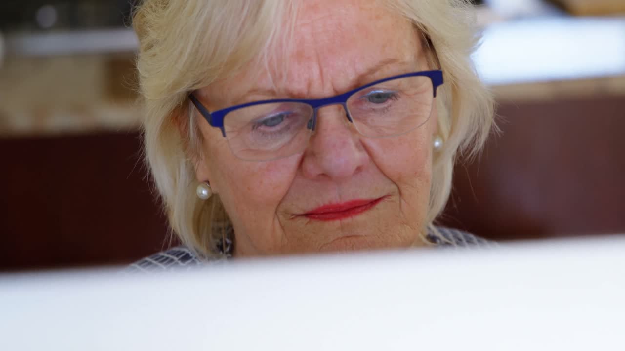 Senior woman using computer at home 4k