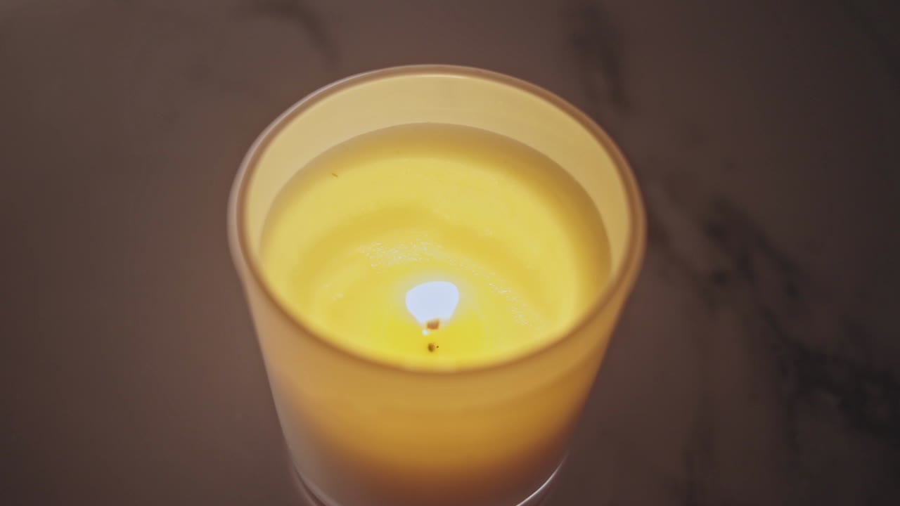 Candela in un bicchiere accesa con sfondo bokeh.