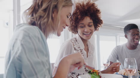 Grupo-De-Jóvenes-Amigos-Sentados-Alrededor-De-La-Mesa-En-Casa-Disfrutando-De-Una-Comida-Juntos