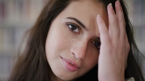 retrato de cerca de una mujer joven y linda, una estudiante sonriente, con la mano corriendo por el cabello, una chica adolescente bonita, con pecas, en cámara lenta.