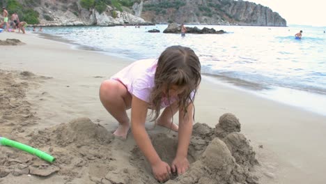 Niña-Jugando-En-La-Playa-Construyendo-Castillos-De-Arena