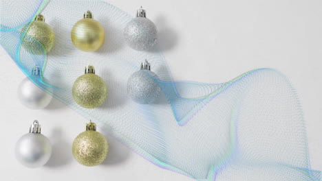 animation of trails of blue light over christmas baubles decorations