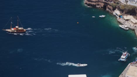 High-Angle-Closer-Wide-Shot-of-Boat-Leaving-The-Harbour-of-Thira-in-Santorini-Greece