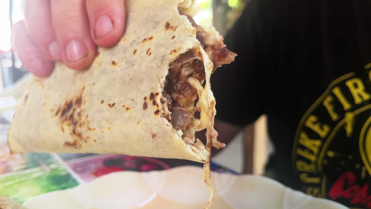 turista comiendo tortillas o tlayudas de comida tradicional mexicana llenas de carne