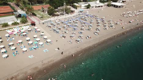 Vista-Aérea-De-Arriba-Hacia-Abajo-De-Personas-Tomando-El-Sol-En-Un-Complejo-Privado-En-Bech,-En-El-Mar-Adriático-De-Montenegro,-Destino-De-Vacaciones-En-Becici.