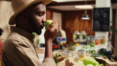 male customer enjoying fresh smell of green apples in crates