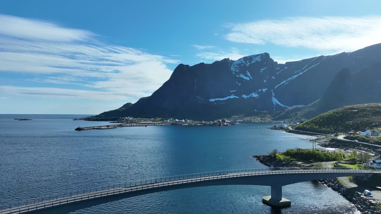 Reine bridge over Reinefjorden with traffic, Reinebringen mountain and village in Lofoten spring