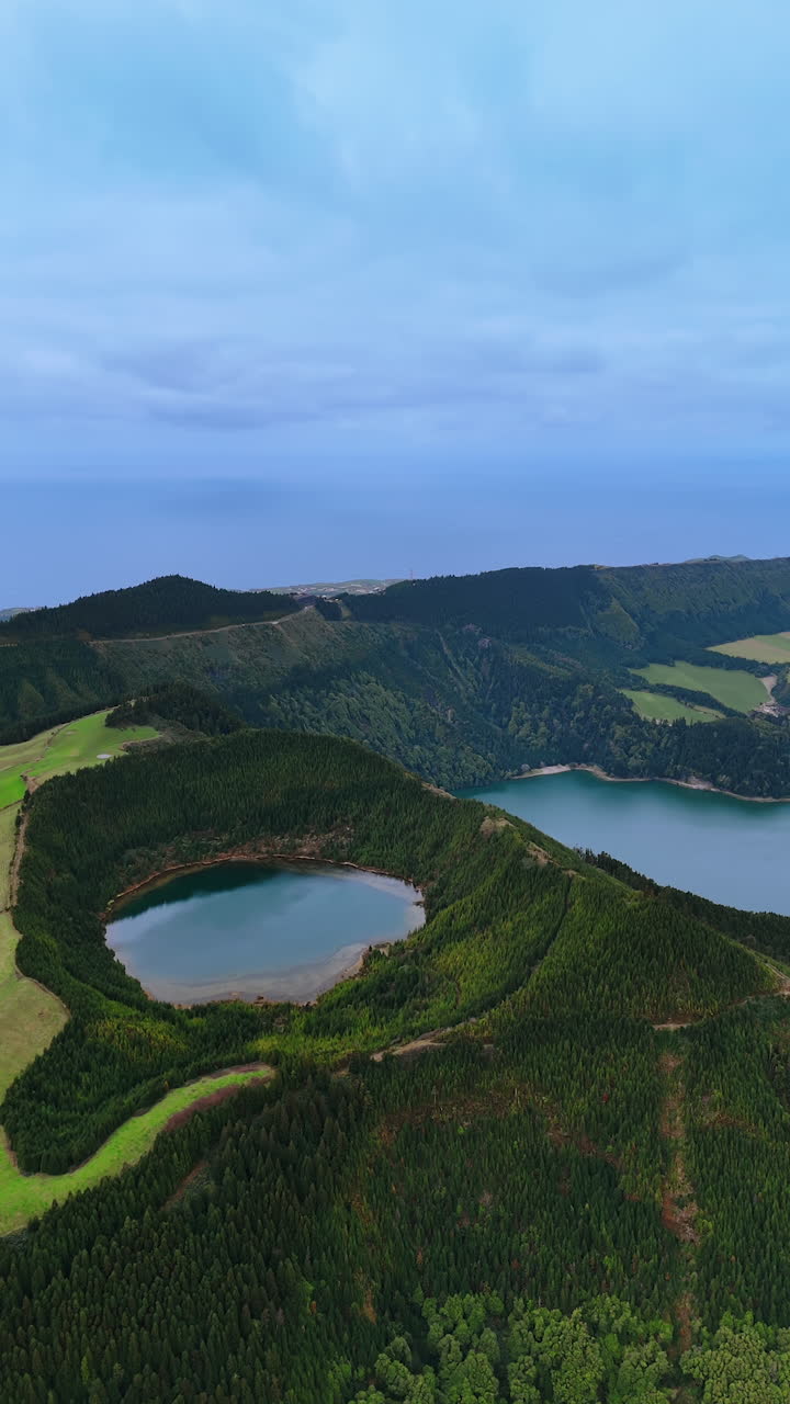 Scenic view of a lake located in the crater of a sleeping volcano. Mountains of the Azores covered with lush greenery. Top view. Vertical video.