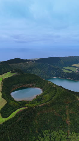 scenic view of a lake located in the crater of a sleeping volcano. mountains of the azores covered with lush greenery. top view. vertical video.