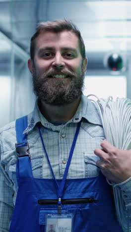 bearded technician holding cables in a server room