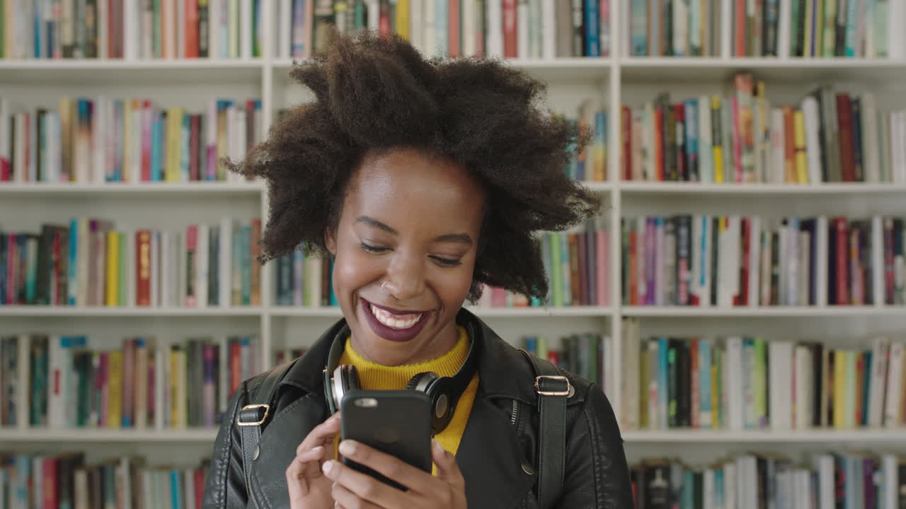 Portrait African American woman student using smart phone bookshelf library university