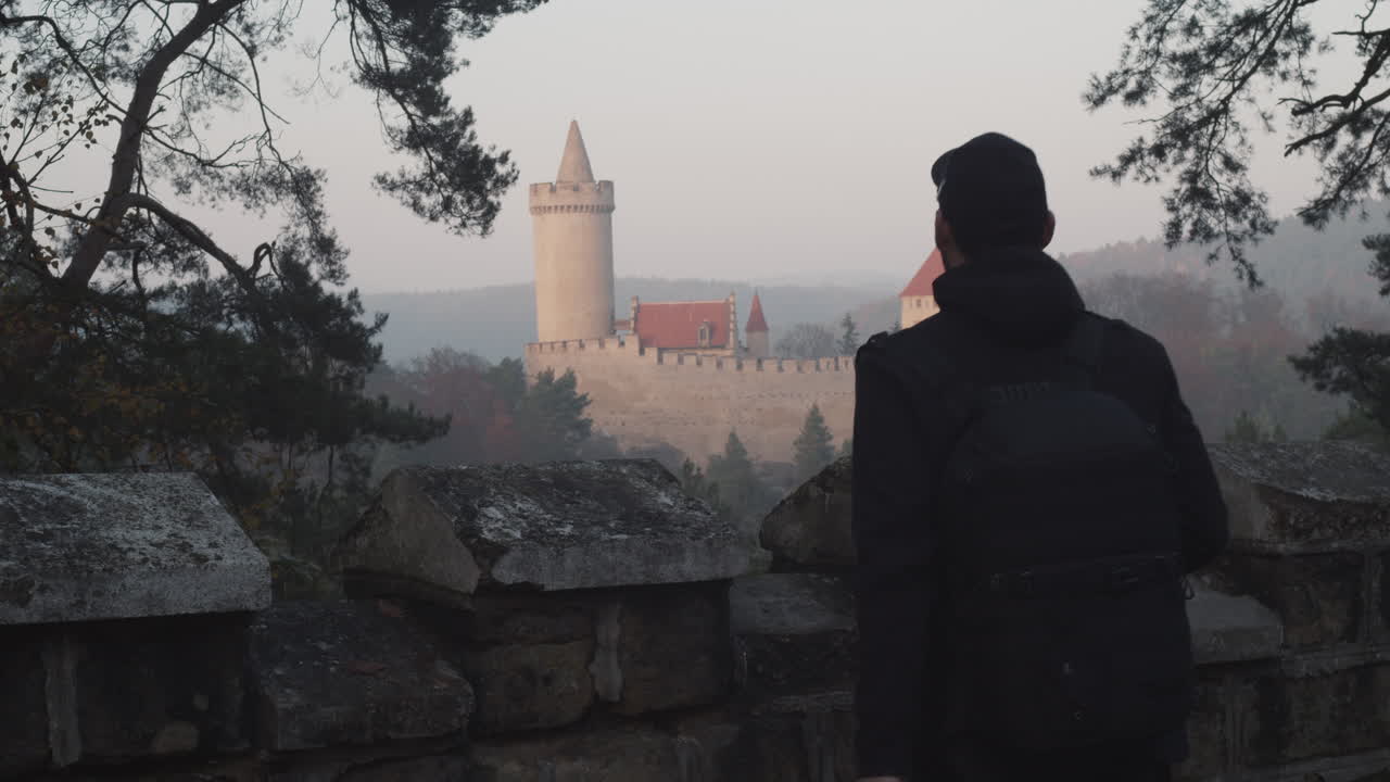 Male photographer taking photo of Kokorin castle in background, Czech Republic, middle shot