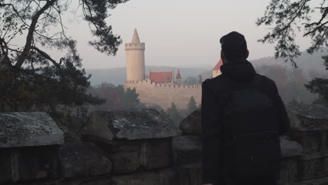 Fotógrafo-Masculino-Tomando-Fotos-Del-Castillo-De-Kokorin-En-El-Fondo,-República-Checa,-Plano-Medio