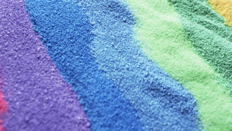 Video-of-close-up-of-rainbow-coloured-sand-grains-and-copy-space-background