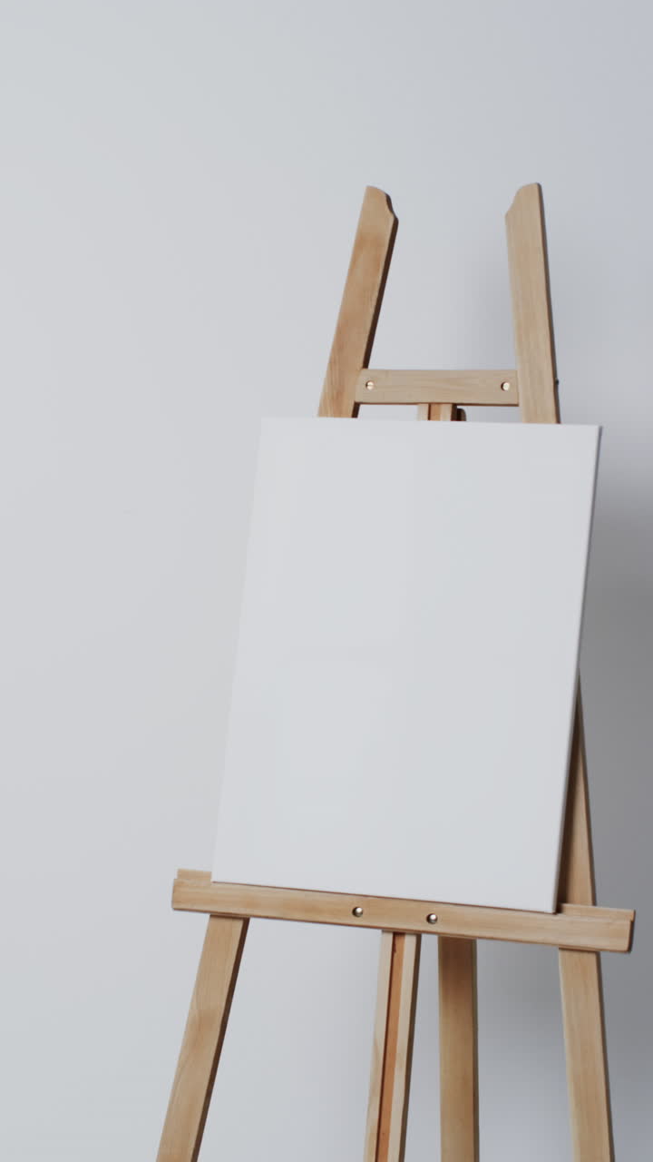 Vertical video of white canvas sign on wooden easel with copy space on white background