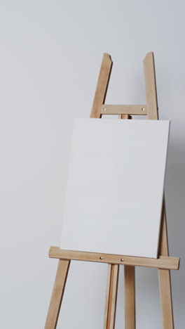 vertical video of white canvas sign on wooden easel with copy space on white background