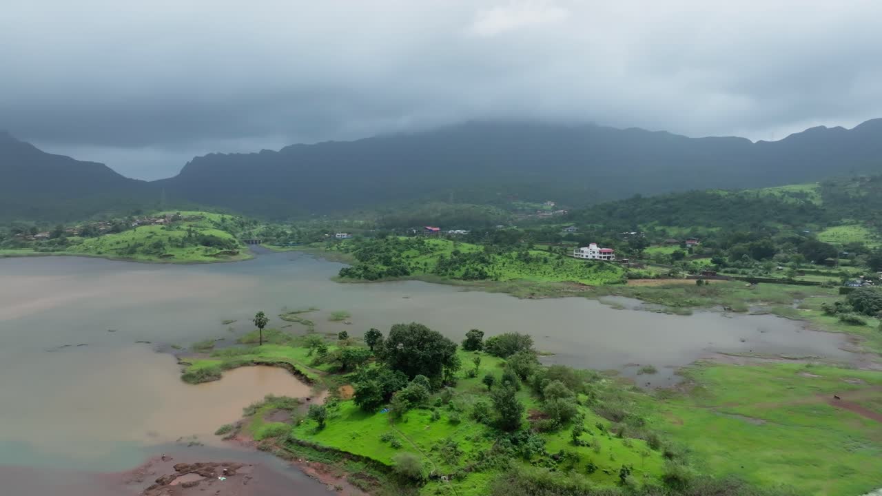 Cảnh quay drone sau mùa gió mùa lia máy qua phong cảnh Maharashtra xanh tươi, với một vùng nước có đảo nhỏ, những cánh đồng nông nghiệp, những dãy đồi và khu định cư nông thôn gần Pháo đài Vikatgad Peb.