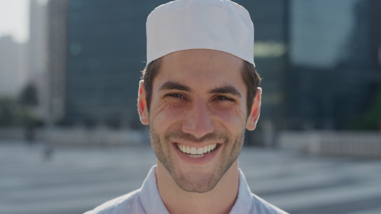 초상화 예쁜 젊은 아랍 사업가 웃는 행복한 기업가 도시에서 전문적인 도시 생활 방식을 즐기는 무슬림 남자가 쿠피 모자를 입고 슬로우 모션