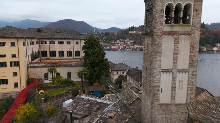 Drone che sorvola la storica basilica e il monastero sull'Isola di San Giulio. Vista dettagliata dell'antica architettura sul Lago d'Orta in Piemonte. Ideale per la storia e i viaggi in Italia.