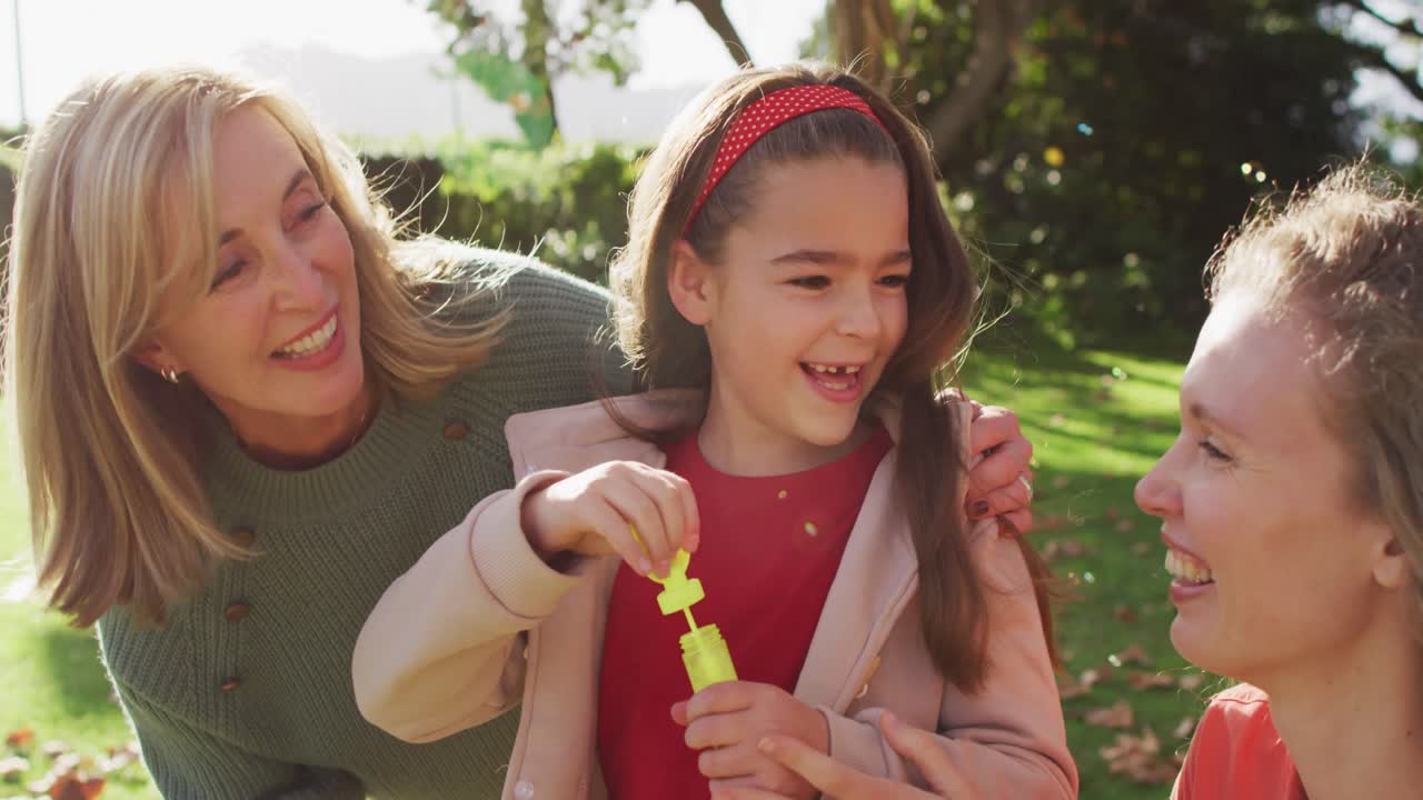 웃는 백인 손녀가 정원에서 어머니와 할머니와 함께 거품을 불어넣는 동영상