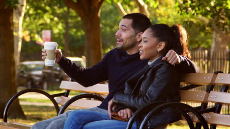 una joven pareja hispana se sienta hablando en un banco en el parque de brooklyn.