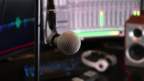 Smooth-tracking-shot-of-a-microphone-in-close-up,-with-computer-monitors-in-the-background