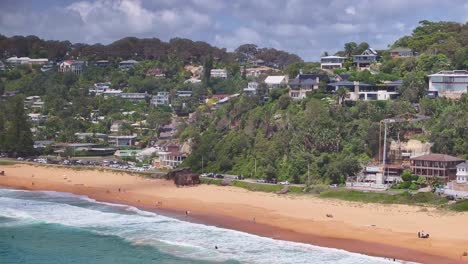 Reveal-of-houses-on-the-cliff-at-Palm-Beach-and-beach-goers-on-the-sand-and-in-the-water