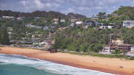 revelación de casas en el acantilado en palm beach y visitantes de la playa en la arena y en el agua
