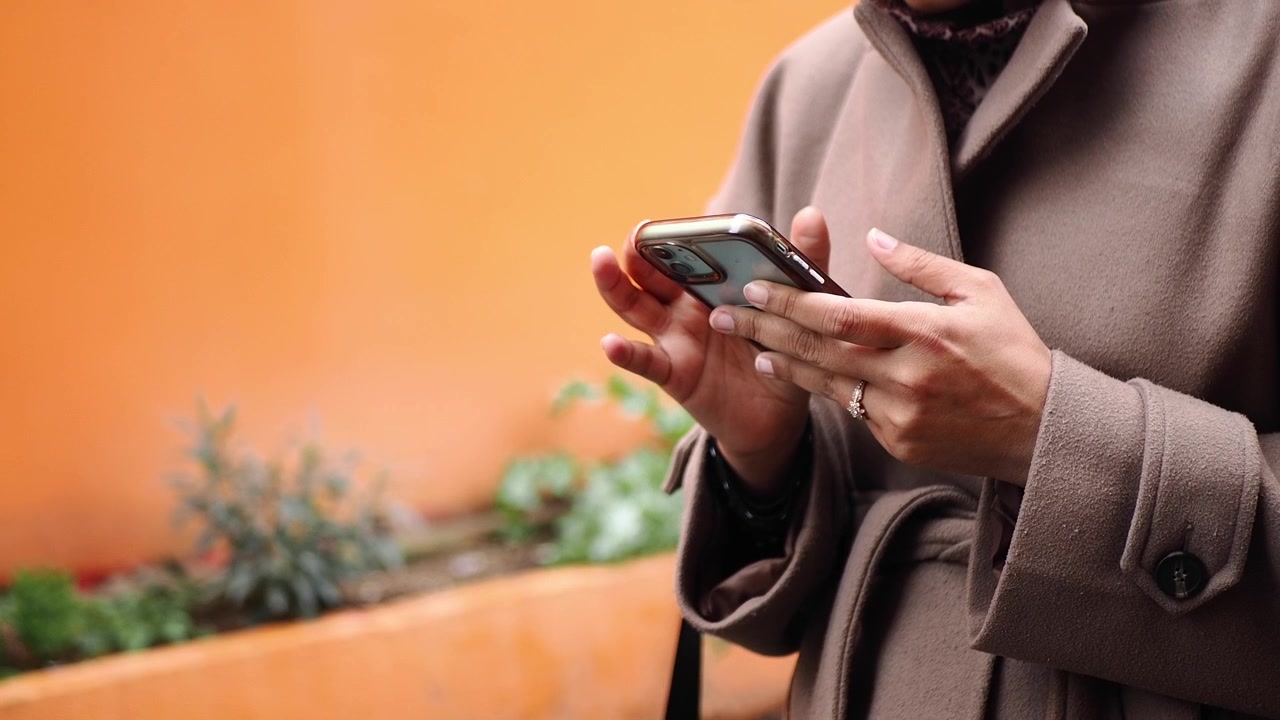 Person Using Smartphone Outdoors in Casual Attire