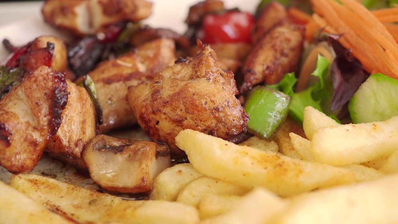 Fork picking up green pepper from a plate of grilled chicken shish kebab