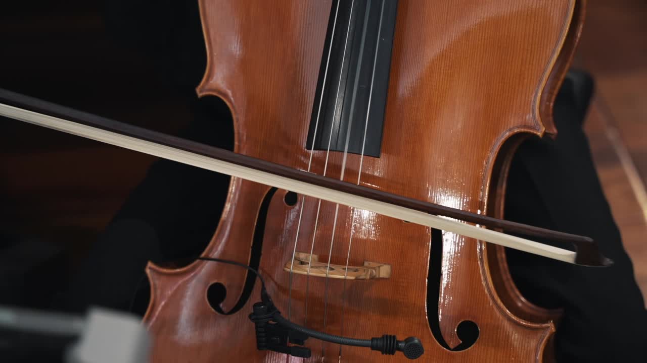 Close-up of a cellist's hand playing a wooden cello with a bow