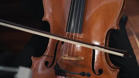 close-up of a cellist's hand playing a wooden cello with a bow