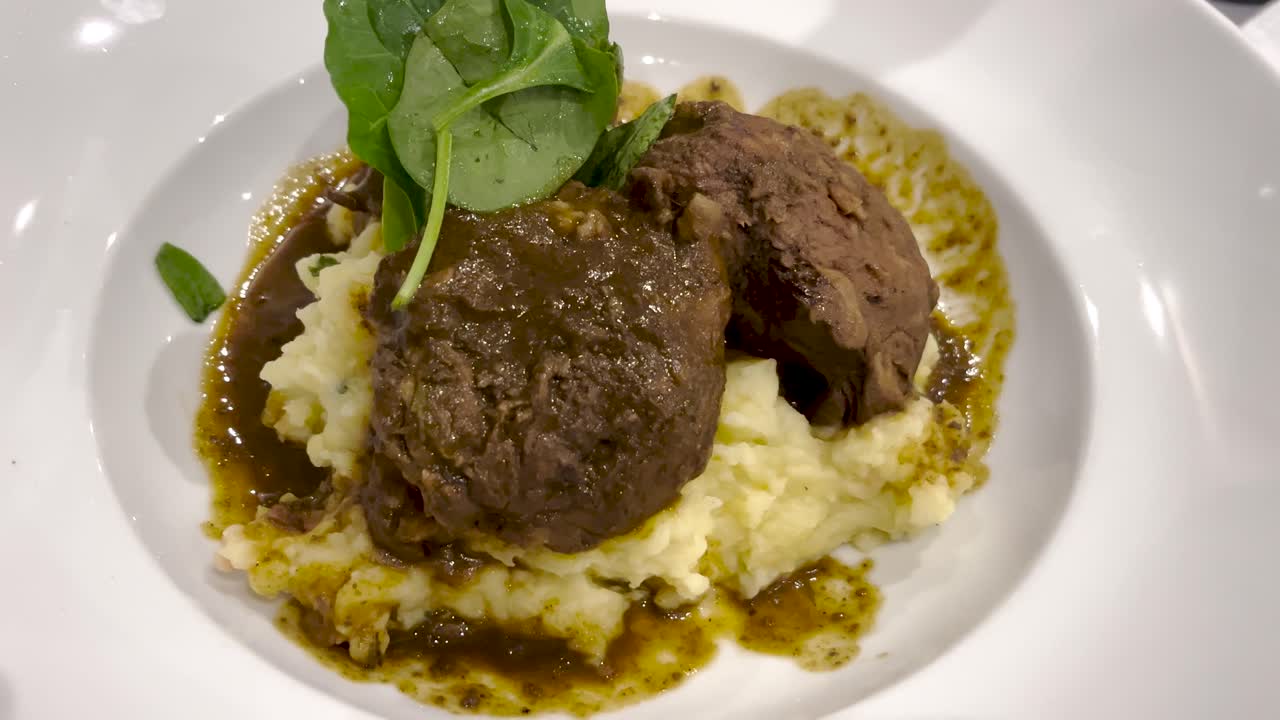 Smooth and Creamy Potato Puree Topped with Tender Meatballs, Drizzled in Rich Tomato Sauce, and Garnished with Fresh Basil Leaves