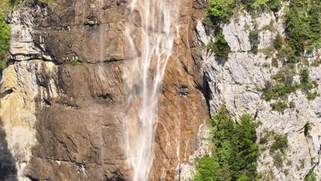 close-up drone view of seerenbachfälle waterfall streaming over swiss rock cliffs, beside dense green forest in betlis, walensee, switzerland