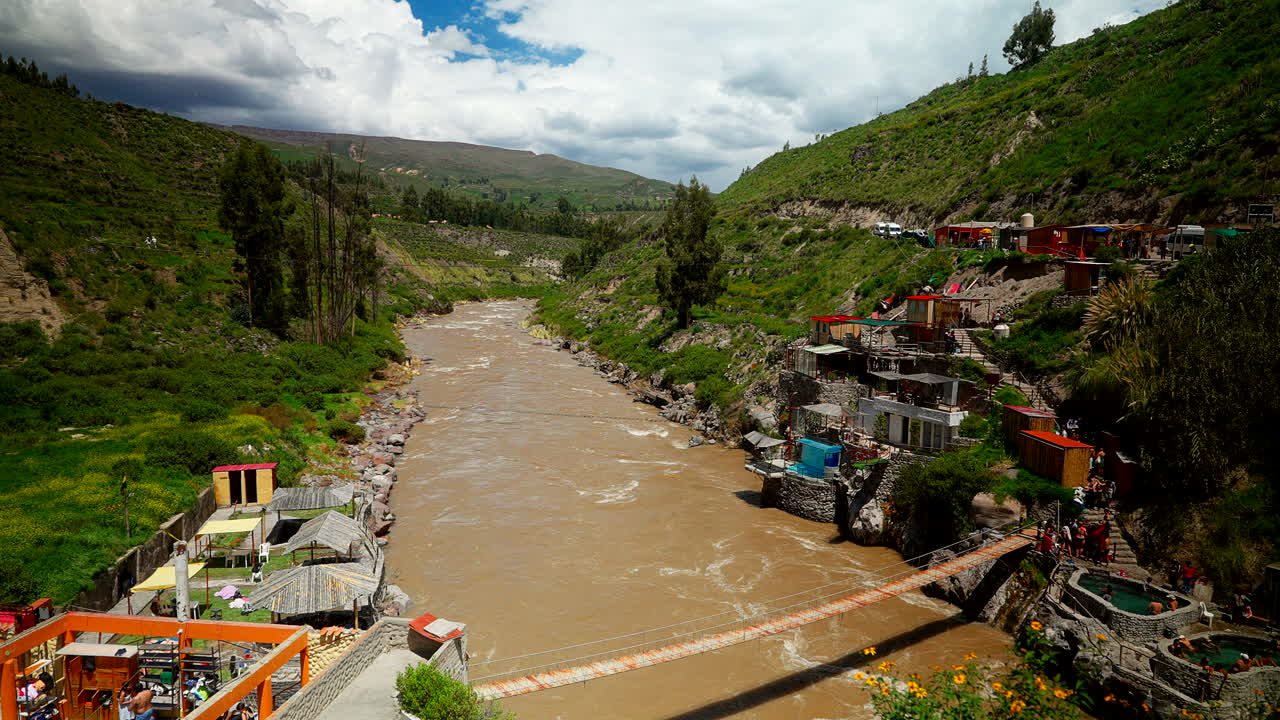 Vista panoramica del fiume fangoso che scorre sotto un ponte ai Baños Termales de Chacapi vicino a Chivay nella regione del Canyon del Colca in Perù, Sud America
