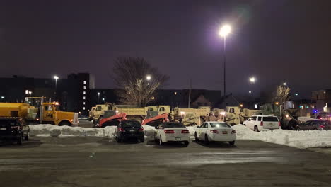 heavy equipment consisting of excavators and a snow plow ready for the street on a cold night