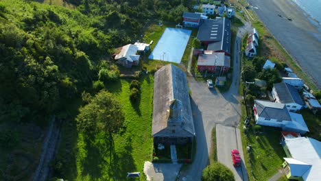 Aerial-view-circling-the-Detif-main-church,-on-Lemuy-island,-sunny-Chiloe,-Chile