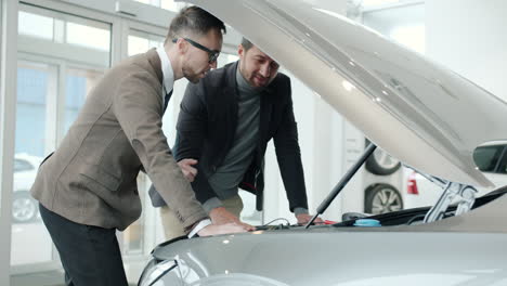 two men inspecting a car in a showroom