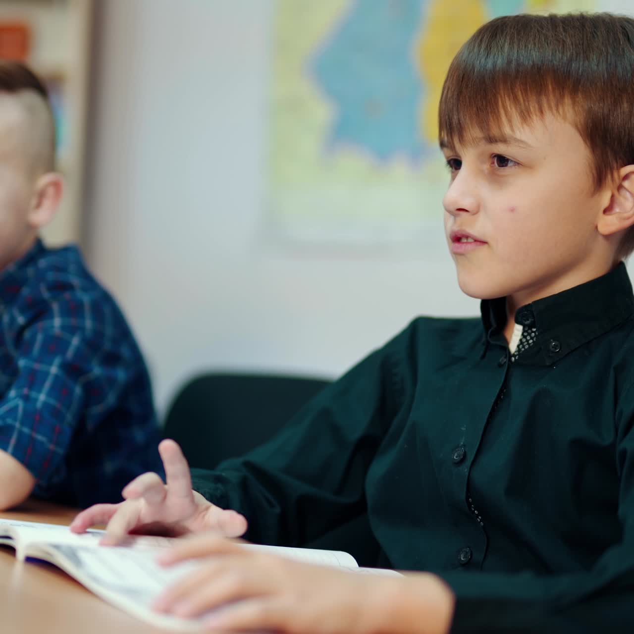 Primary schoochildren in the classroom. Smart boys sitting at the desk and studying at school. Back to school education concept.