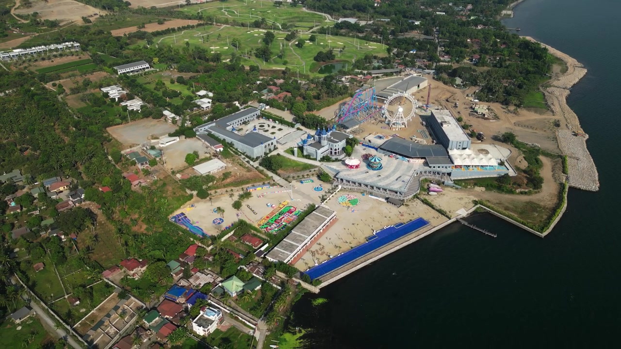 Suave ascenso de dron con retroceso que revela el horizonte completo del lago, la propiedad del resort y el paisaje montañoso en Tanuan, Batangas, Filipinas.
