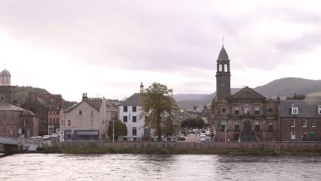 panning shot of church steeple along the river ness with hills in the background in inverness, scotland in the highlands