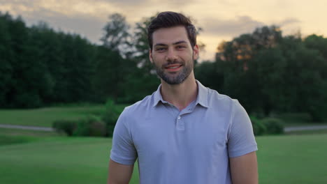 happy model smiling outside. handsome sportsman standing on golf course sunset.