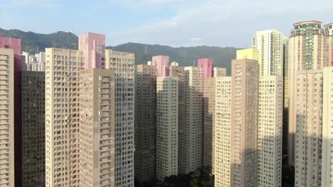 Mega-residential-buildings-in-downtown-Hong-Kong-and-Lion-rock-mountain-ridge-in-the-background,-Aerial-view