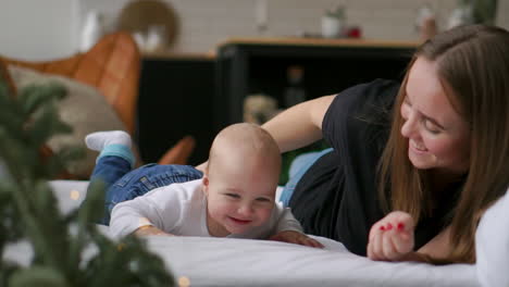 young mother hugging her newborn child. mom nursing baby. woman and new born boy relax in a white bedroom. family at home. love, trust and tenderness concept. bedding and textile for nursery.