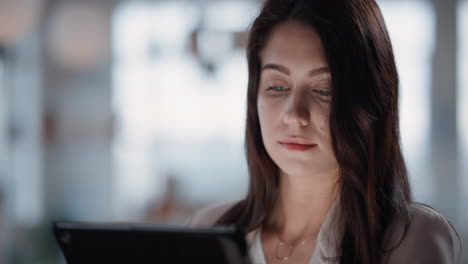 Mujer-De-Negocios-Joven-Que-Usa-Una-Tableta-Y-Trabaja-Hasta-Tarde-En-La-Oficina-Navegando-Por-Información-Mirando-Datos-En-Una-Pantalla-Táctil-Digital