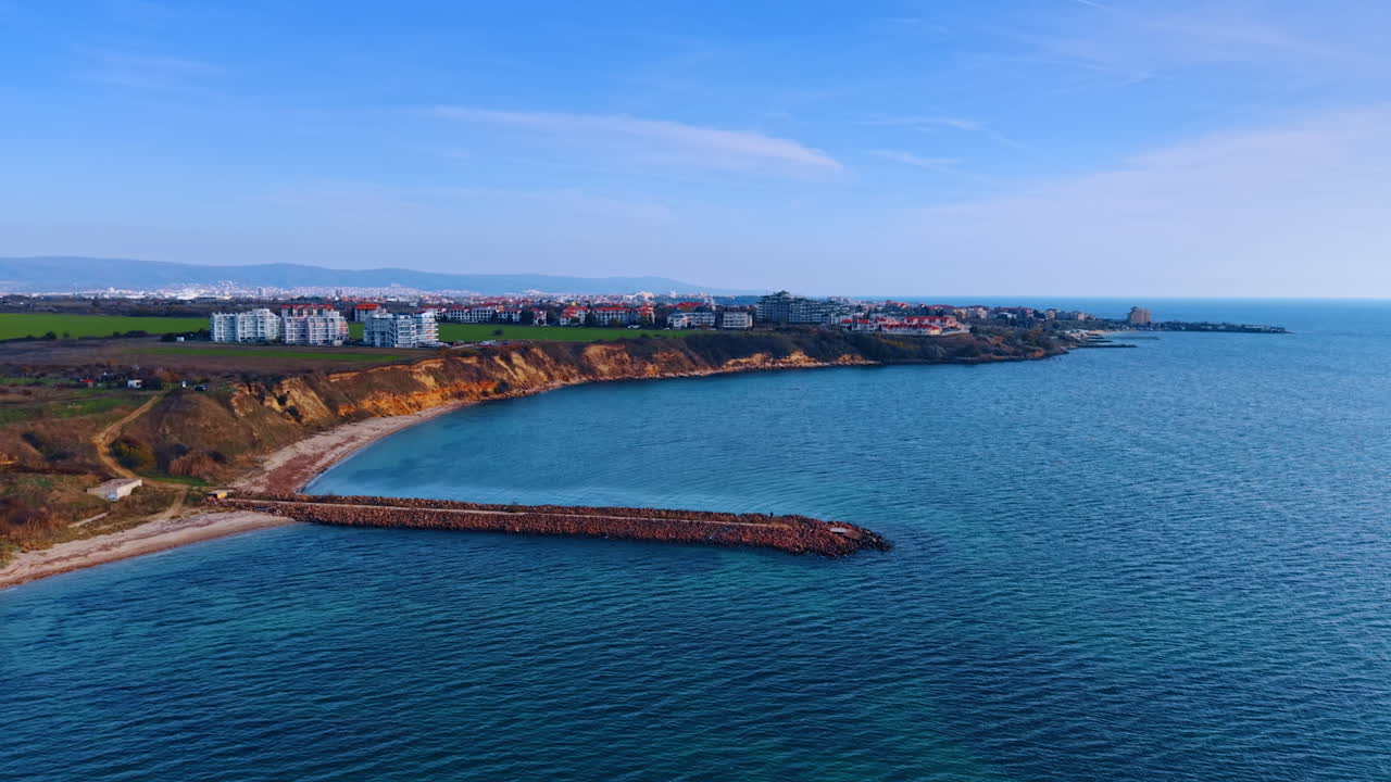 Lungo molo nel paesaggio acquatico blu. Vista suggestiva sul paesaggio urbano situato sulla riva del mare