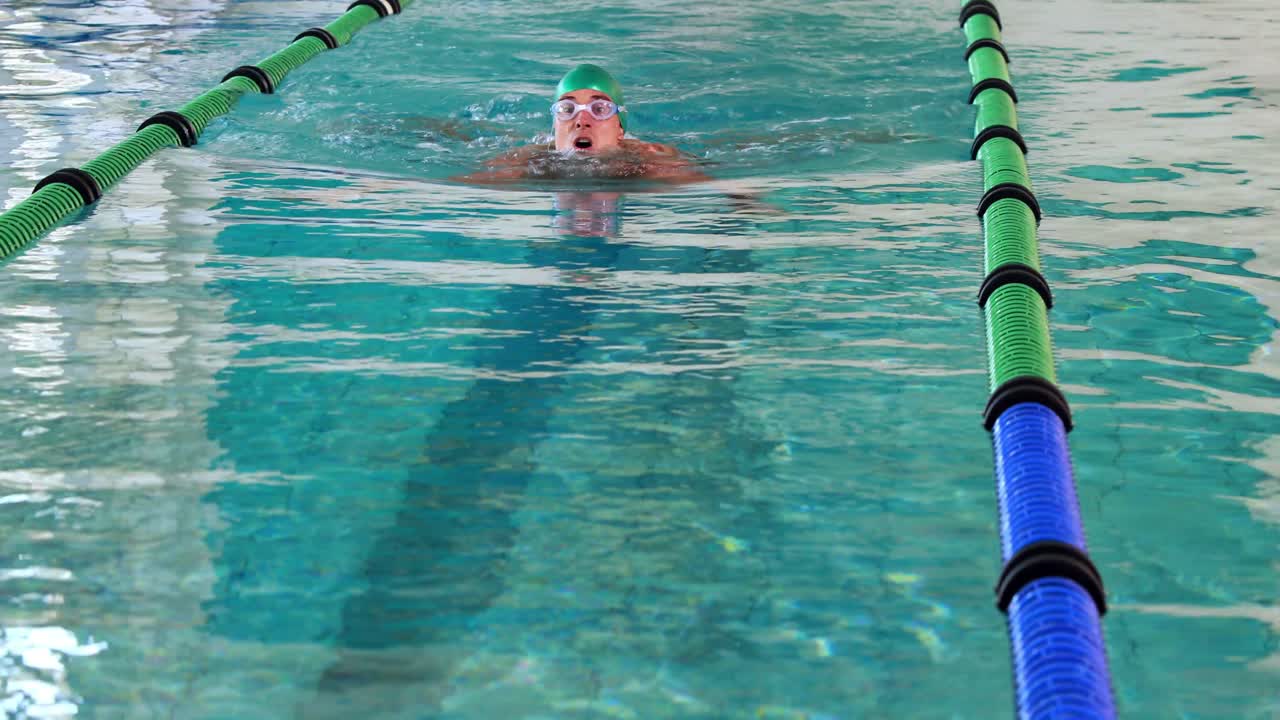 подходящий пловчик делает грудной удар в бассейне