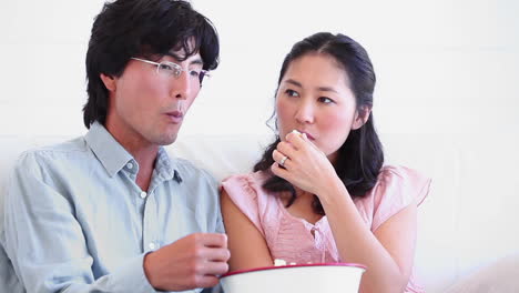 man and a woman eating a bowl of popcorn