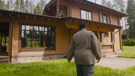 Smiling-Middle-Aged-Woman-Waving-Outside-Home-And-Then-Going-Inside